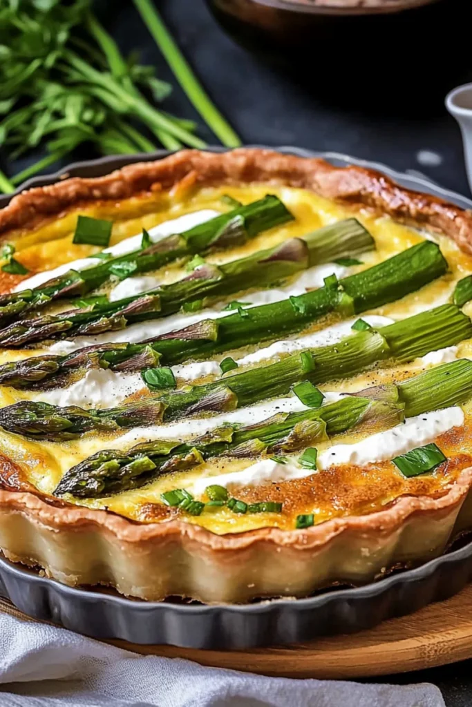 Eine knusprige Spargelquiche mit grünem Spargel, cremiger Füllung und goldbraunem Teig, garniert mit frischen Kräutern. Die Quiche liegt in einer runden Backform auf einem Holzbrett, umgeben von frischen Kräuterzweigen.