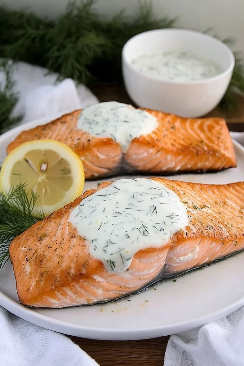 „Gegrillter Lachs mit Zitronen-Dill-Sauce, serviert mit Zitronenscheiben und frischem Dill.“