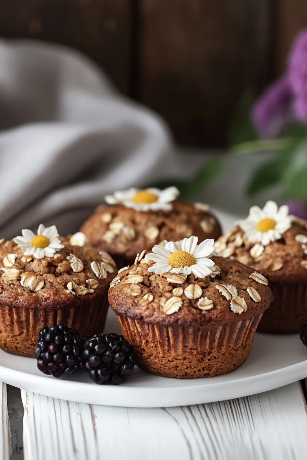 Frisch gebackene Haferflocken-Muffins in einer dunklen Muffinform, goldbraun gebacken und mit ganzen Haferflocken bestreut.